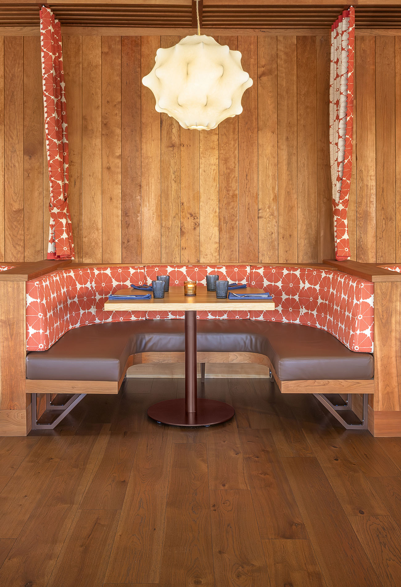 Workind Studio interior for Solana Beach restaurant, LANA. The design features custom horseshoe-shaped booths. Fabric decorated with pop art orange flowers brightens the cherry and walnut wood finishes.